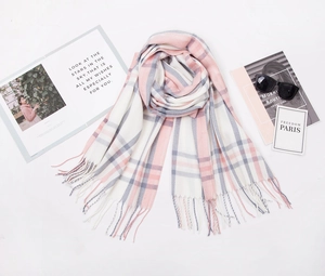 Close-up of soft plaid scarf with pink and grey patterns, fringe detail, and fashion props