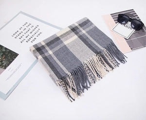 Detail of soft cashmere-like fabric with black and white plaid texture and fringe edges