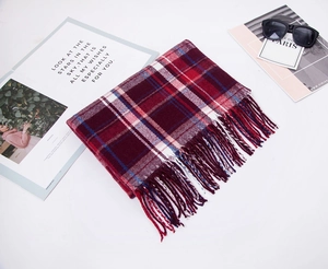 Detailed flat lay of red plaid cashmere-like scarf with tassels and fashion sunglasses