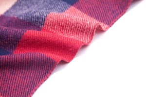 Macro detail of red and blue plaid scarf showing soft cashmere texture and twill weave