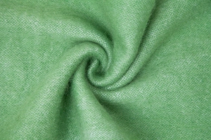 Close-up of soft grass green striped mohair-like knit fabric with fluffy plush texture