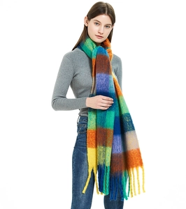 Close-up of thick mohair scarf featuring vibrant rainbow checkered pattern and long tassels