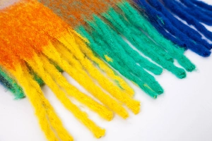 Close-up of rainbow checkered mohair scarf showing thick tassels and soft fluffy texture