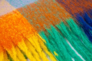 Close-up of rainbow mohair scarf texture featuring vibrant fringe and soft fiber details