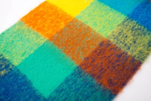 Close-up of thick mohair scarf featuring vibrant rainbow plaid pattern and fuzzy texture