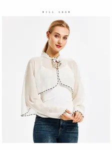Detail of off-white chiffon shawl featuring polka dot trim and a delicate bow neckline