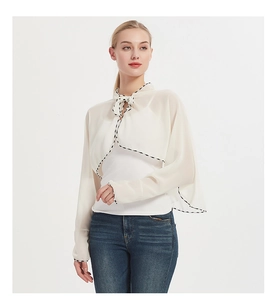 Detail of white chiffon sun protection shrug with woven trim and front tie closure