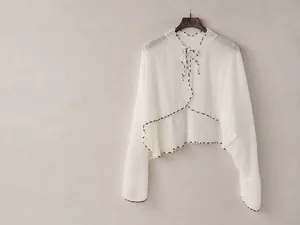Detail of white chiffon sun protection shawl with floral piping and bow tie collar