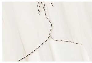 Detail of cream chiffon fabric with ethnic braided rope accent on sun protection shawl