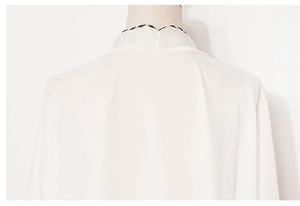 Detail of white chiffon sun protection shawl with scalloped black and white trim collar