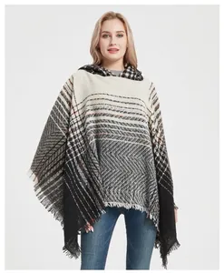 Detail of hooded poncho cape featuring black and white herringbone pattern with fringe trim
