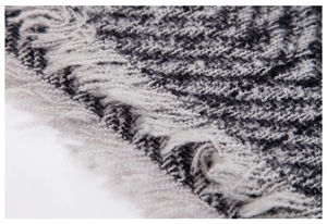 Close-up of herringbone knit texture and soft fringe detail on grey hooded poncho