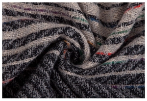 Close-up of thick herringbone knit cape with colorful striped yarn and spiral texture