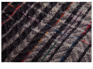 Detailed macro shot of thick knit herringbone poncho fabric with colorful yarn fibers