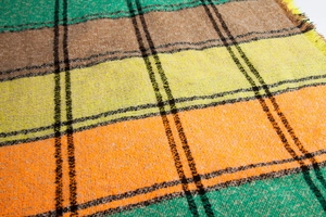 Macro shot of colorful large check knit pattern with thick fringe detail on shawl