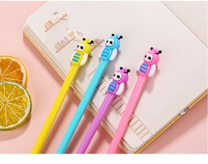 Set of four colorful bee-themed gel pens featuring cute 3D toppers on a pink notebook