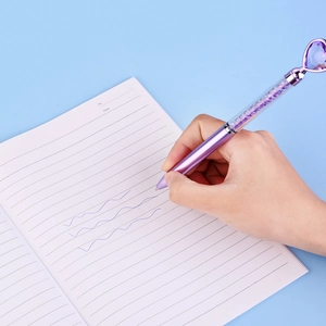 Detail of hand writing with a purple heart-shaped crystal pen with sparkling floating sand