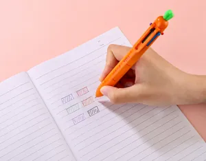 Primer plano de mano sujetando bolígrafo de zanahoria con 6 colores en libreta