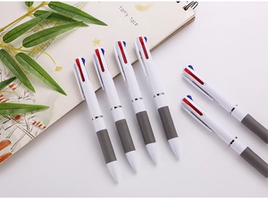 Stylos à bille trois couleurs avec grip gris antidérapant sur un bureau blanc