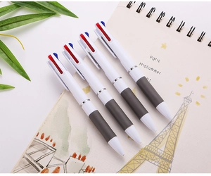 Gros plan de quatre stylos à bille 3 couleurs avec poignées en caoutchouc sur un carnet