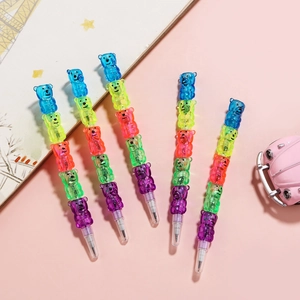 Flat lay of five stackable cartoon bear pencils in vibrant colors on a pink desk background