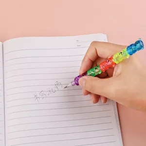 Close-up of hand writing with a multi-colored stackable bear pencil on a notebook
