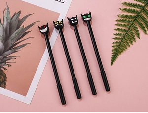 Close-up of cute devil character pens with colorful monster head toppers on pink surface
