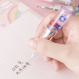 Lipstick-shaped gel pen with shimmering beads held in hand for smooth writing on paper