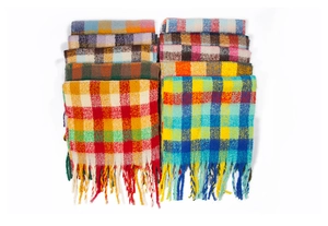 Detail of colorful plaid scarves featuring soft knit texture and long tassel edges