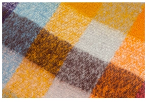 Macro shot of thick colorful plaid scarf featuring soft brushed wool texture and fringe