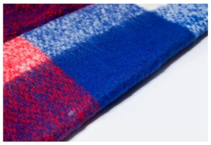 Macro shot of thick fringe details and fuzzy plaid wool-like knit fabric on poncho