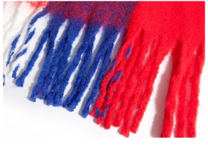 Detail of color-block knit poncho with soft textured yarn and long fringed tassels