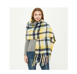 Macro detail of oversized check scarf featuring yellow and blue plaid with thick tassels
