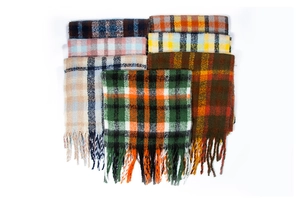 Detailed view of colorful plaid scarves featuring long thick tassels and fuzzy texture