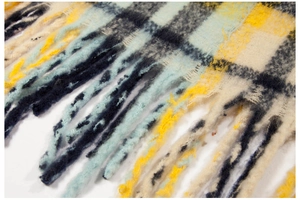 Macro shot of plaid scarf fringe showing soft fiber texture and thick woven tassels