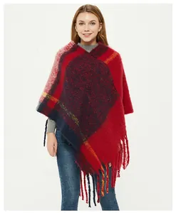 Detail of red and navy plaid knit poncho featuring elegant long fringe hem and thick yarn