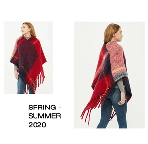 Detail of red and blue checkered knit poncho with thick tassels and chunky yarn texture
