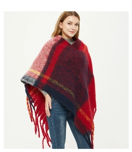 Close-up of knit poncho featuring red and blue plaid patterns with long fringe details