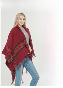 Detail of red tartan hooded poncho showing soft cashmere-like fabric and fringe tassels