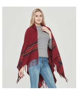 Detail of red knit shawl featuring colorful stripes and thick fringe trim for winter