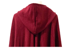 Detail of burgundy hooded poncho showing high-quality knit texture and hood seam