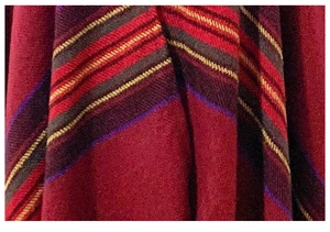 Detailed close-up of heavy-knit fabric with colorful ethnic stripes in dark red and purple