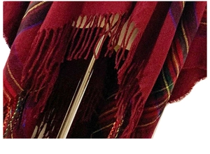 Close-up of red and black plaid shawl fabric showing soft texture and tassel details