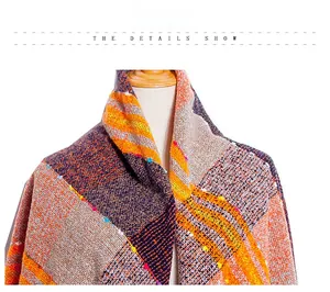 Detailaufnahme von grobem Strickschal mit buntem Gittermuster und kleinen Bommeln