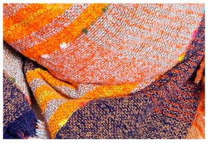 Makroaufnahme eines dicken Strickschals mit orange-gelb-blauem Karomuster aus Mischgarn