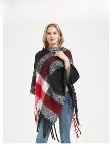 Gros plan du poncho en tricot épais à carreaux rouge et noir avec de longues franges