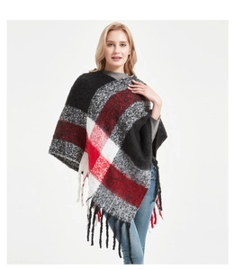 Détail du poncho en tricot à carreaux noir rouge et blanc avec de longues franges