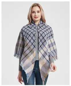Detail of plaid shawl poncho with fringe edges in grey-blue, beige, and brown tones