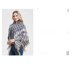 Detail of grey and blue plaid scarf with fine fringe trim and soft knit texture