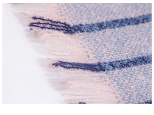 Close-up of pink and blue plaid knit scarf showing soft texture and fringe tassels